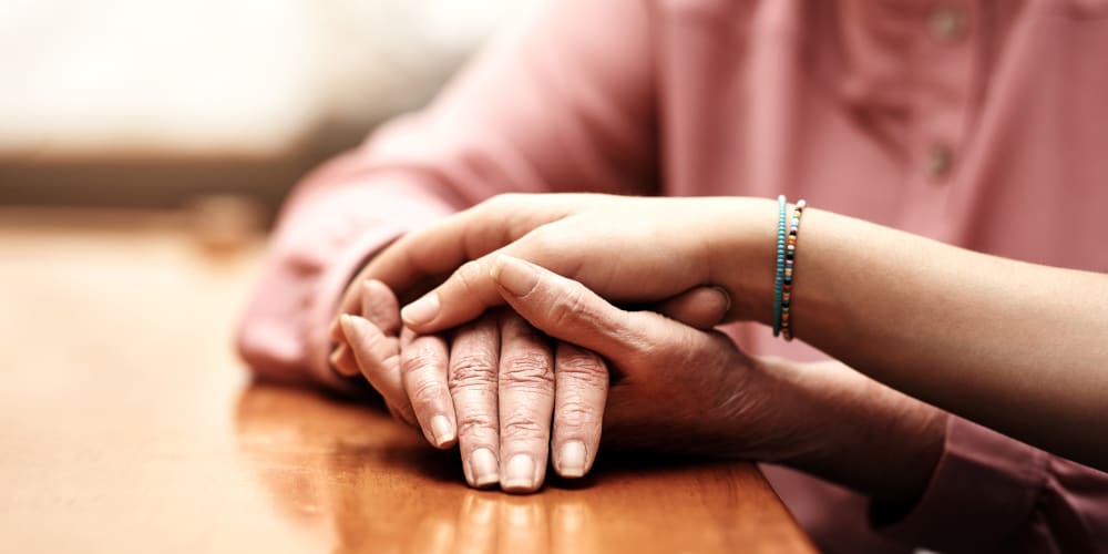 A family member holding a resident's hand at Careage Home Health in Dupont, Washington. 