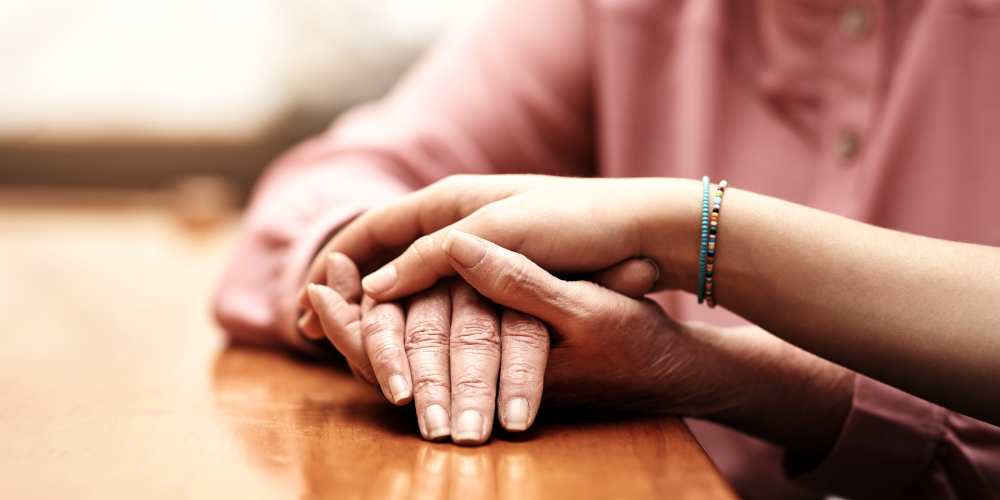 A family member holding a resident's hand at Careage at Home in Bellevue, Washington. 