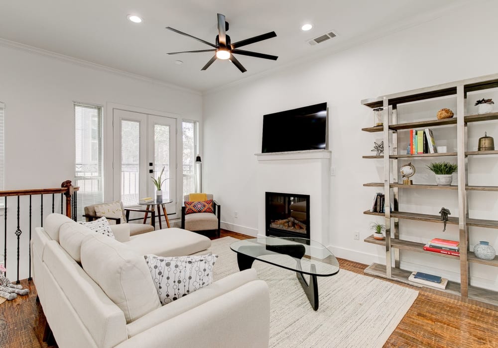 Trendy apartment living room with wooden ceiling fan and glass coffee table at The Collection Townhomes in Dallas, Texas