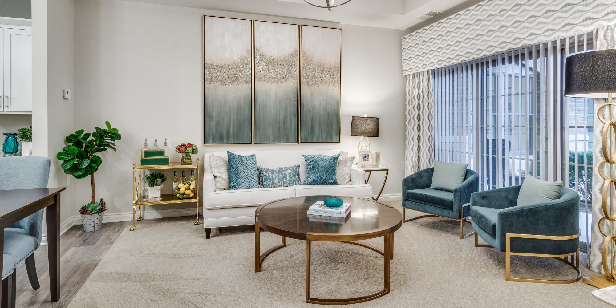 Living room with 2 teal chairs, a circular coffee table, and a white 2 cushion couch at Blossom Collection in Rochester, Michigan