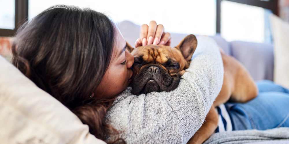 Resident cuddling her pet on a couch in their new apartment at The Calvert in Charlotte, North Carolina