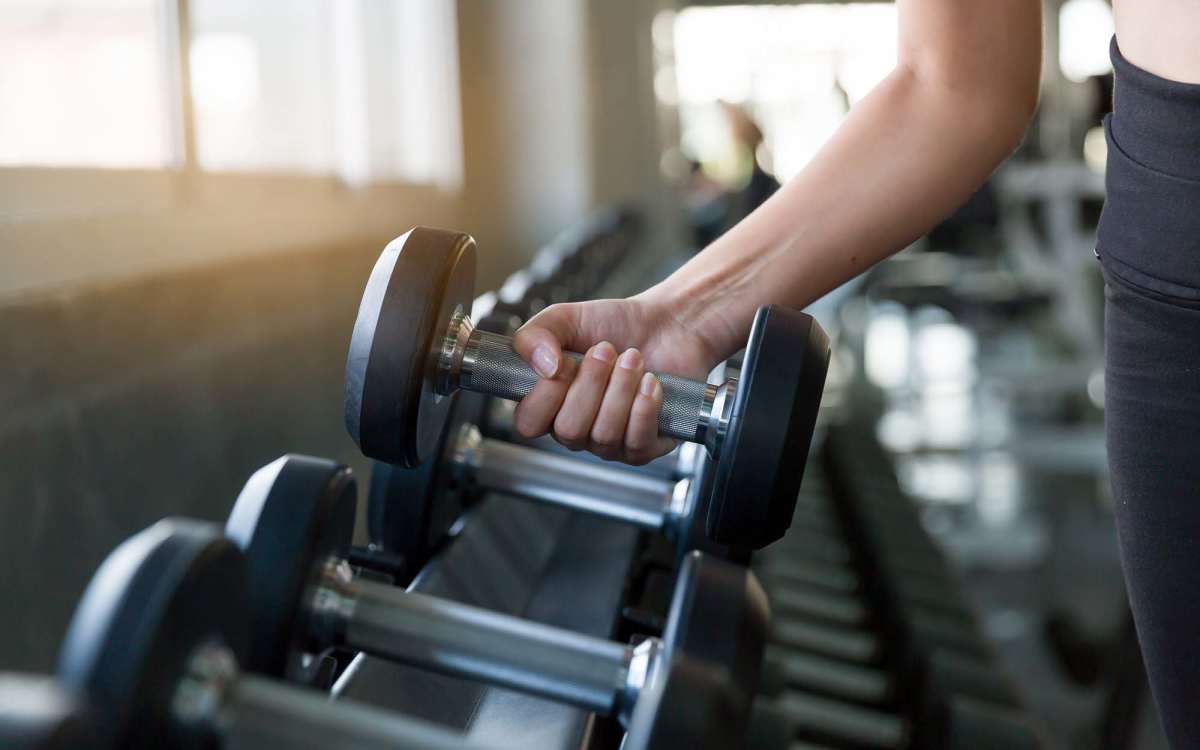 Resident lifting a dumbbell at the fitness center at Pelican Isles Apartments in Sebastian, Florida