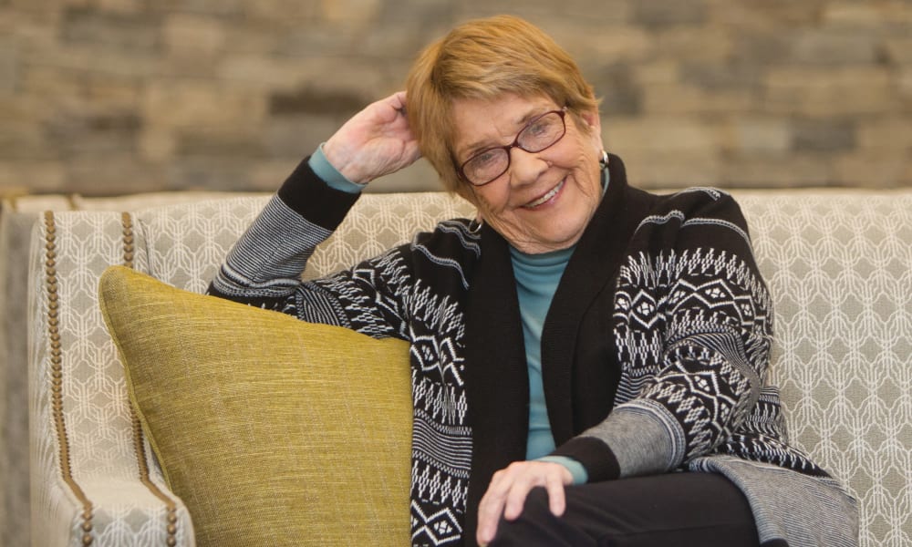 Resident sitting on couch at Maplewood at Brewster in Brewster, Massachusetts