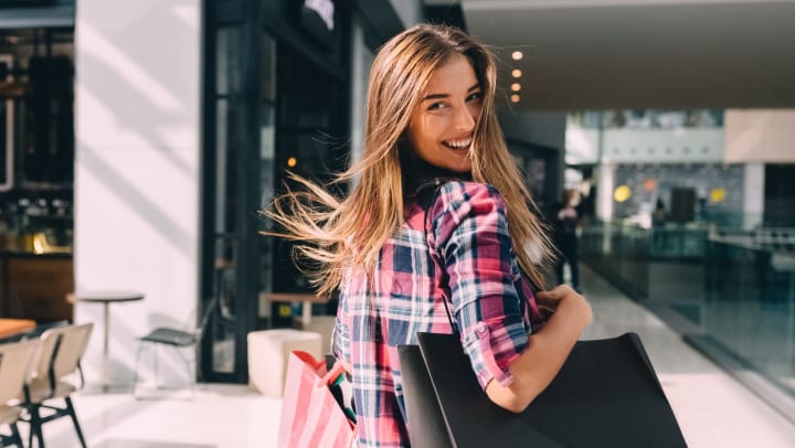 Smiling woman holding shopping bags in a mall.