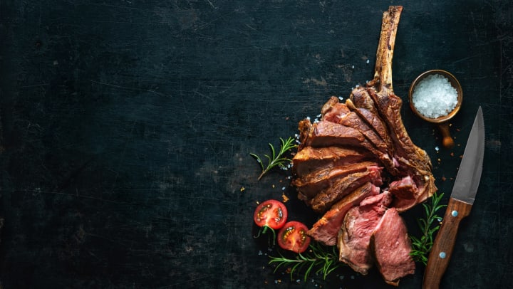 Grilled dry aged tomahawk steak sliced as close-up on dark background