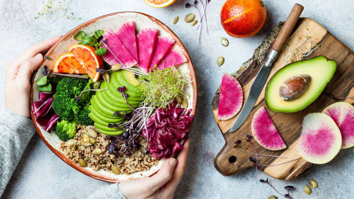 Holding a rice bowl with avocado, broccoli, and radishes | plant-based restaurants in Dallas