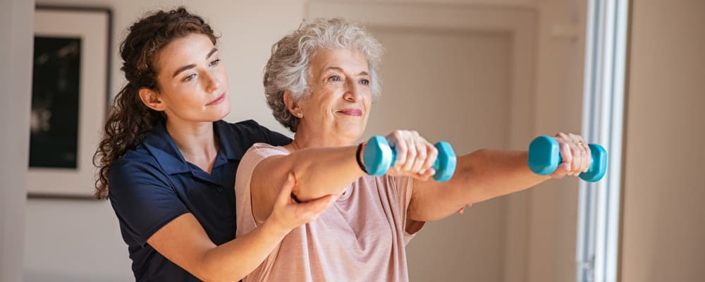 A staff member assisting a resident in exercising at Waverly Place in Albany, Oregon