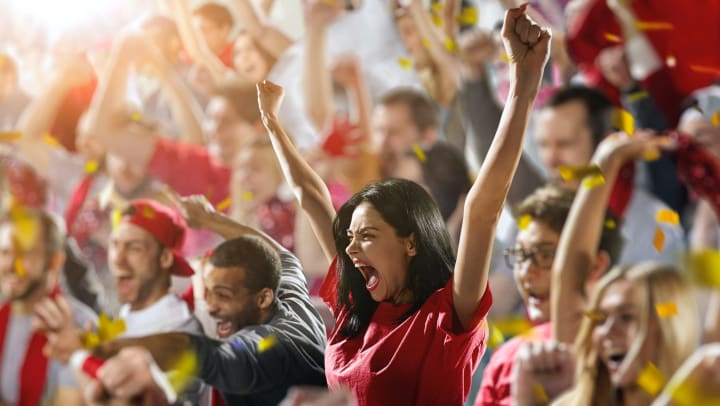 Group of cheering fans watching sports in a stadium