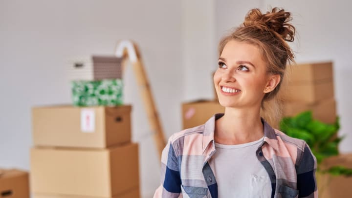 Young woman smiling in new home surrounded by boxes