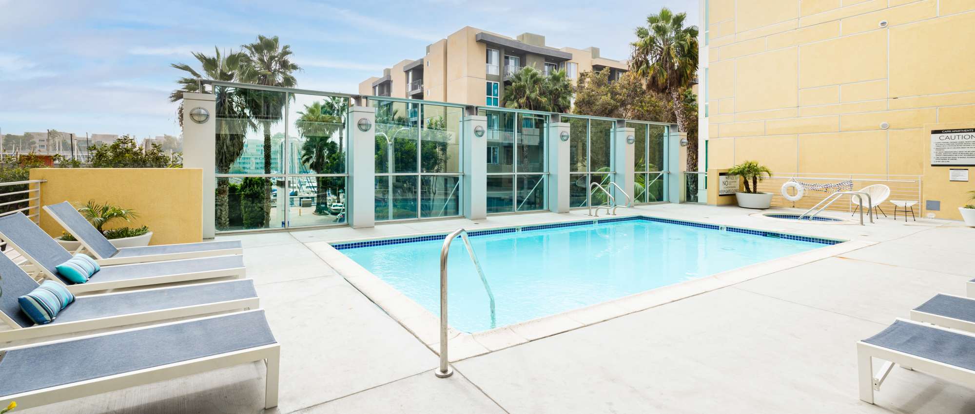 Modern resort-style swimming pool with lounge seating at Capri Apartments in Marina Del Rey, California.
