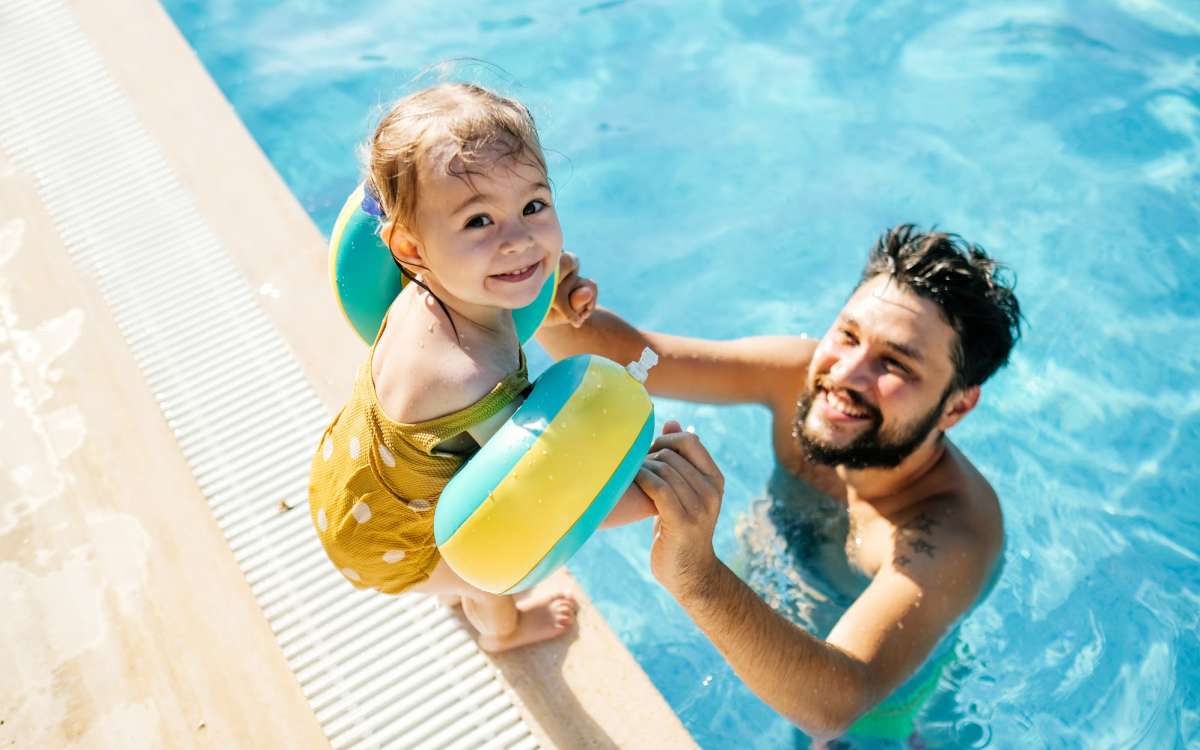 Resident and child using the pool at Woodland Apartments San Antonio in San Antonio, Texas