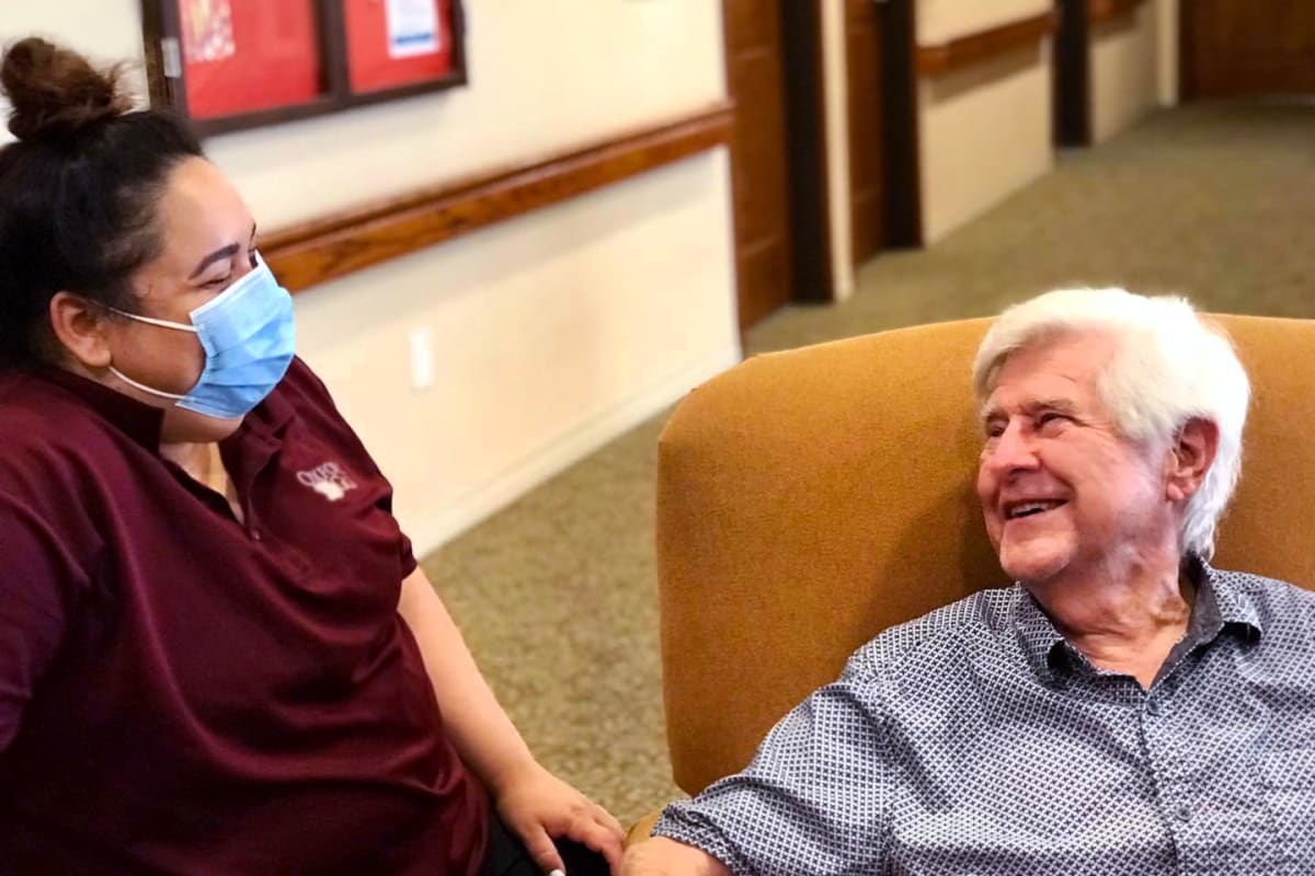 A resident and a caregiver having a nice conversation at Oxford Glen Memory Care at Grand Prairie in Grand Prairie, Texas