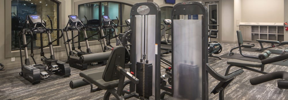 A fitness center with individual workout stations at Sommerall Station Apartments in Houston, Texas