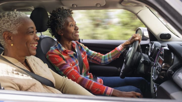 Two older women smiling in a moving car
