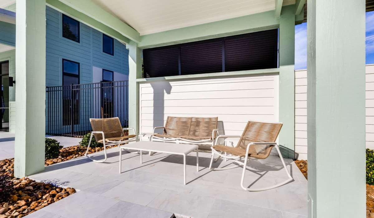Modern patio with three beige woven chairs around a white table on a tiled floor at Trinity Villas in Lafayette, Louisiana