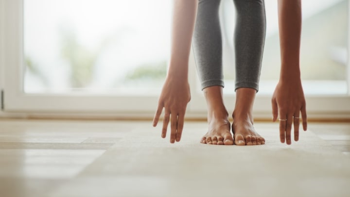 close-up of hands reaching over to touch the floor | how to incorporate movement into routine