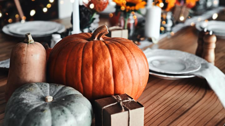 A close-up shot of a wood table set up with fall decor and pumpkins.