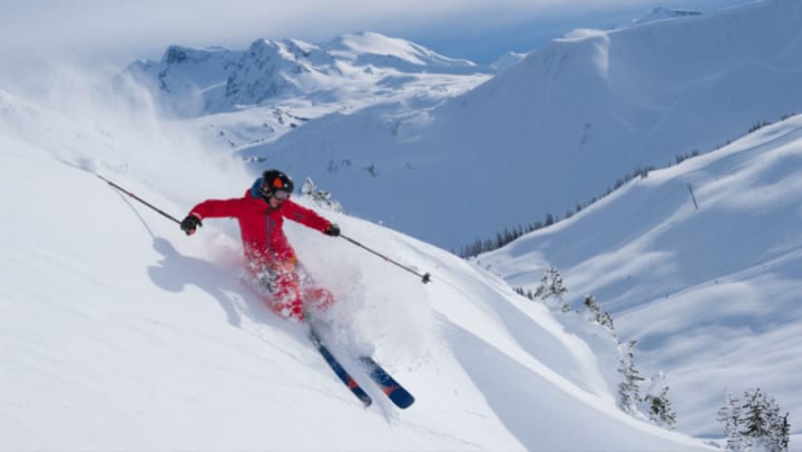 A skier in orange riding down a mountain