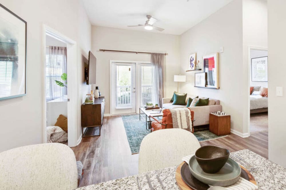 Living area with a ceiling fan and wood-inspired flooring in a model apartment home at Woodside Eleven in Greenville, South Carolina