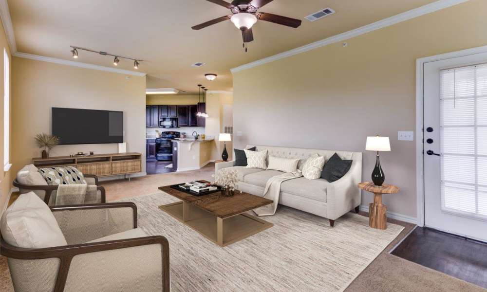 Living room with built-in shelving, wall-to-wall carpeting and a ceiling fan in a model home at Chateau Mirage Apartment Homes in Lafayette, Louisiana