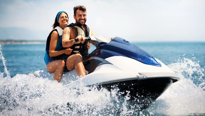 Man and woman riding on a jet ski, smiling.
