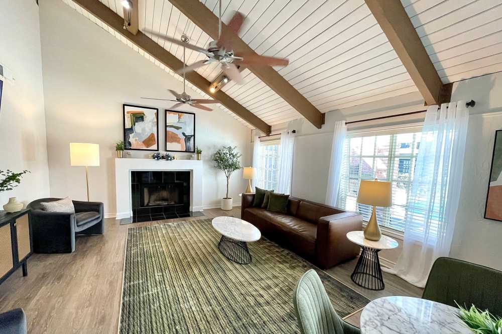 Bright Living Room Featuring Exposed Wooden Beams, Modern Leather Sofa, Coffee Table, And Decorative Art On The Walls at The Abbey at Montgomery Park in Conroe, Texas
