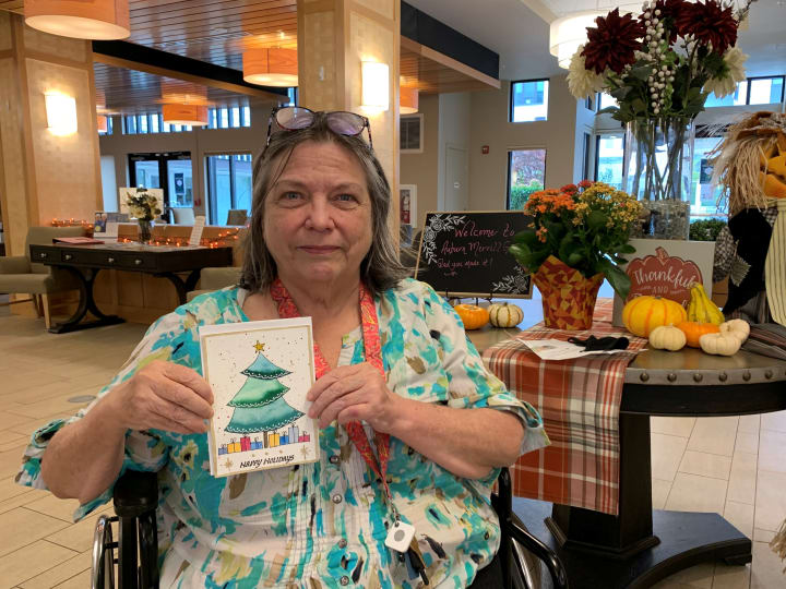 Pat, 2021 Holiday Card Winner, showing off her artwork.