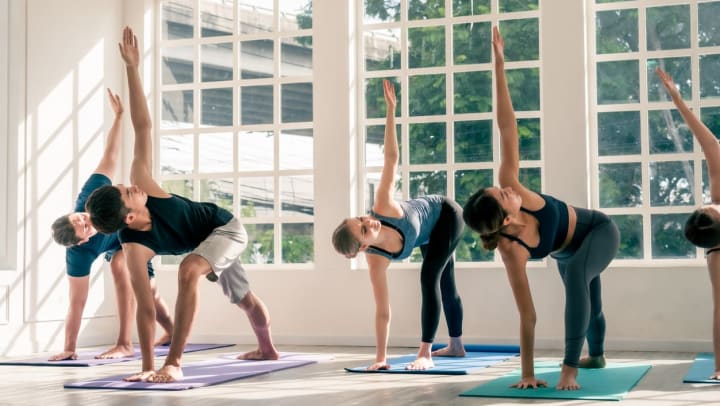 Group of people participate in a yoga class together in a studio room | yoga studios in Southside Jacksonville