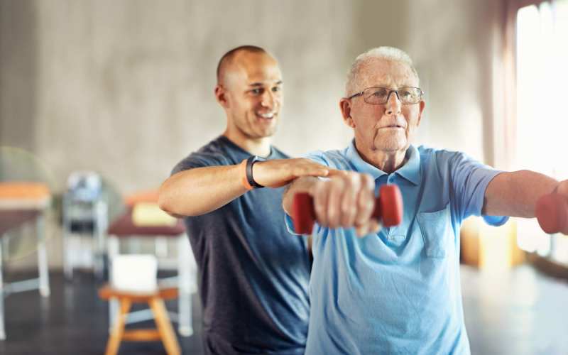 Caregiver helping senior resident to do exercise at Grand Villa of Ocala in Ocala, Florida