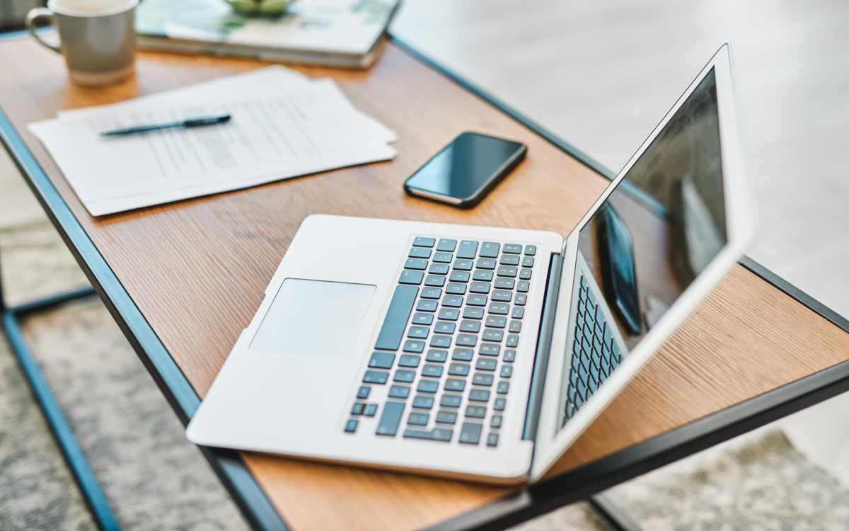 A laptop placed on a work table with papers and a mobile phone at Citron in Omaha, Nebraska