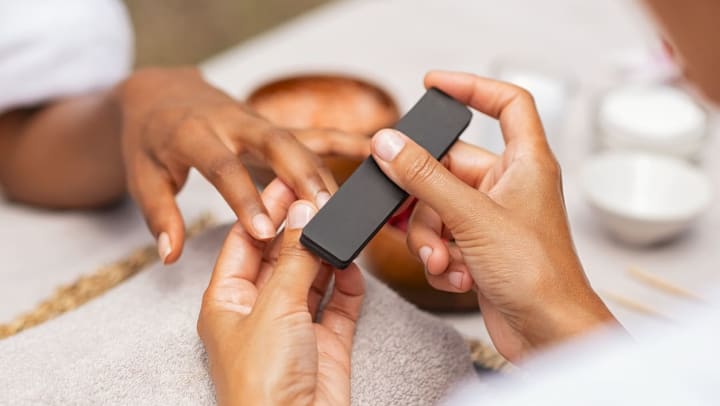 Close up of a manicurist filing a person’s nails | nail salons in The Woodlands