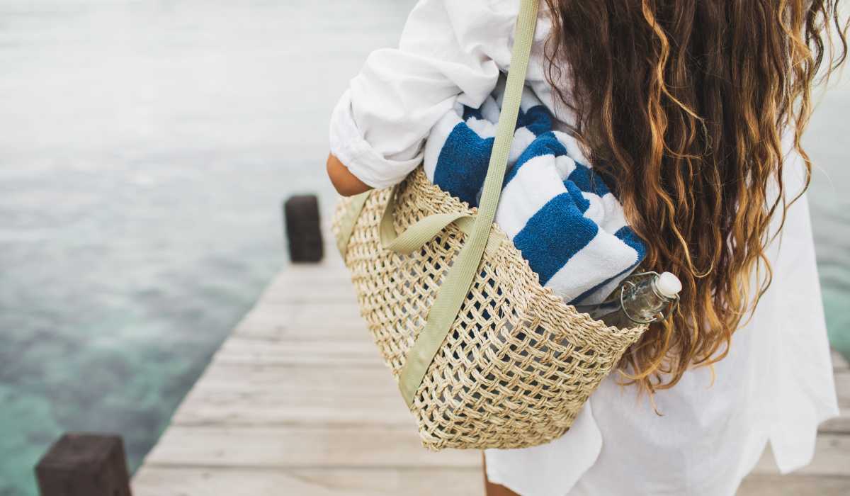 A woman carrying a bag of towels to a dock near Artisan Living North Beach in Santa Rosa Beach, Florida