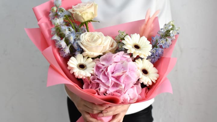 A person holding a pastel floral arrangement from a Sachse florist