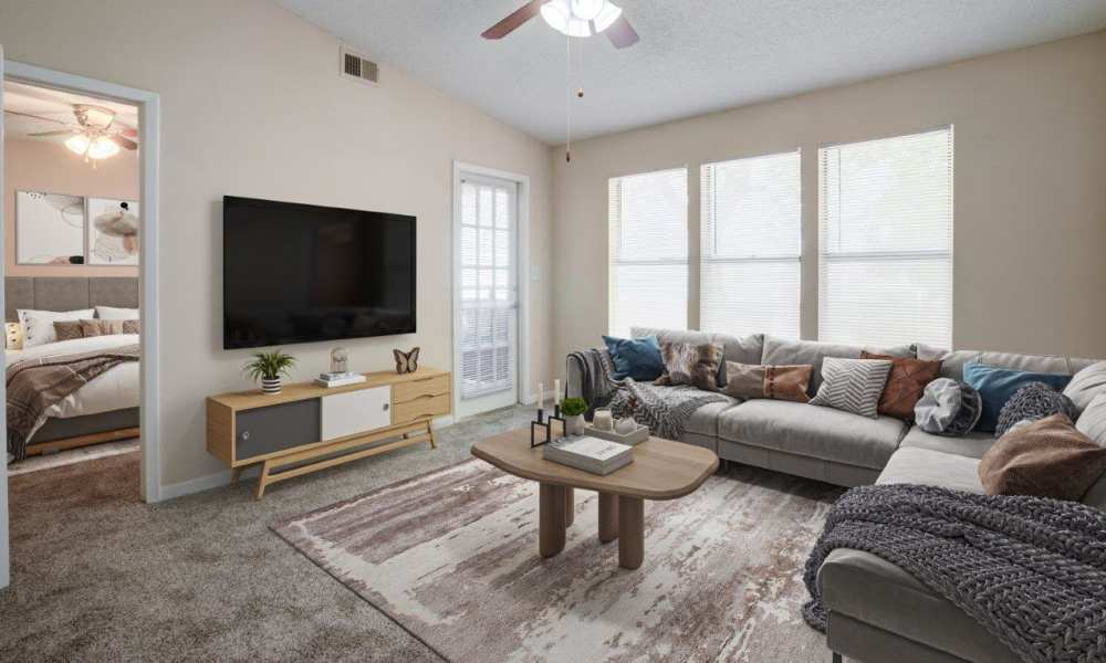 Living room with built-in shelving, wall-to-wall carpeting and a ceiling fan in a model home at Tuscany Pointe at Tampa Apartment Homes in Tampa, Florida