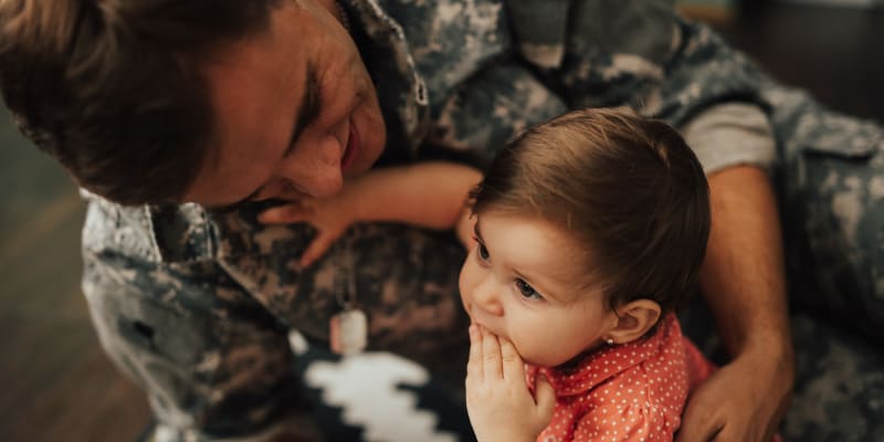 A man in uniform holding his child at O'Neill Heights in Oceanside, California