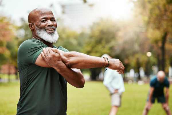 Man stretching on a green lawn outdoors, enjoying fresh air and exercise at Watermere Highlands.