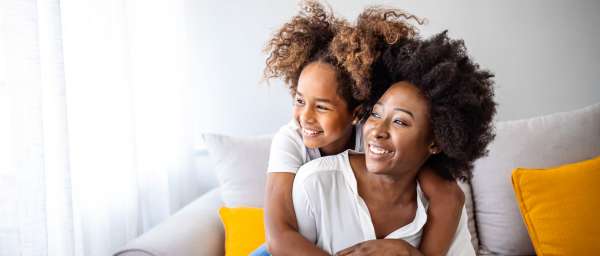 Woman and girl smiling on sofa at home Valley Brook Townhomes in Rochester, New York