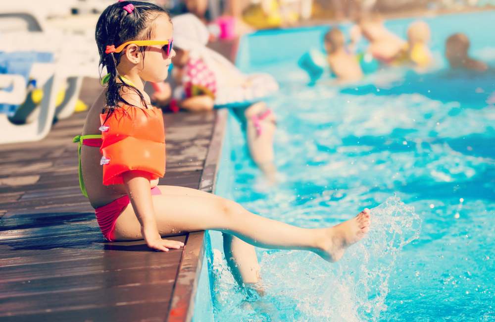 Resident kid sitting on the edge of pool in water park near Natomas Park Apartments in Sacramento, California