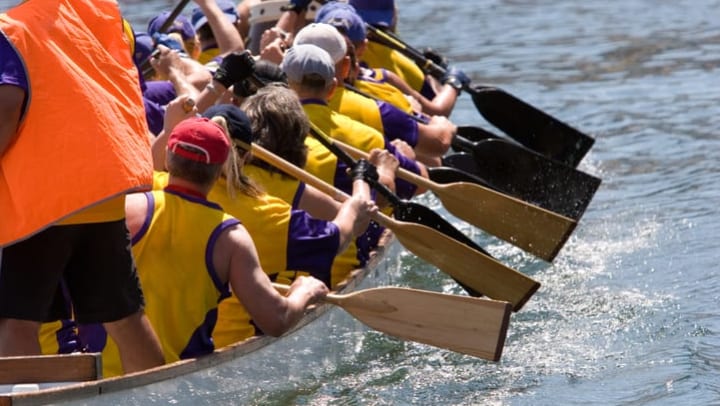 Dragon boat racers paddling near {{location_name}}.