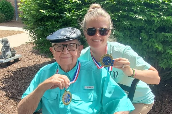 Resident and care taker showing their Olympic medals from Olympic celebration at at The Clinton Presbyterian Community in Clinton, South Carolina.