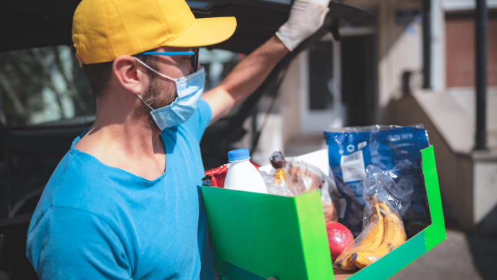 Man handing out a box of groceries to those in need in Keller, Texas near Olympus Waterford