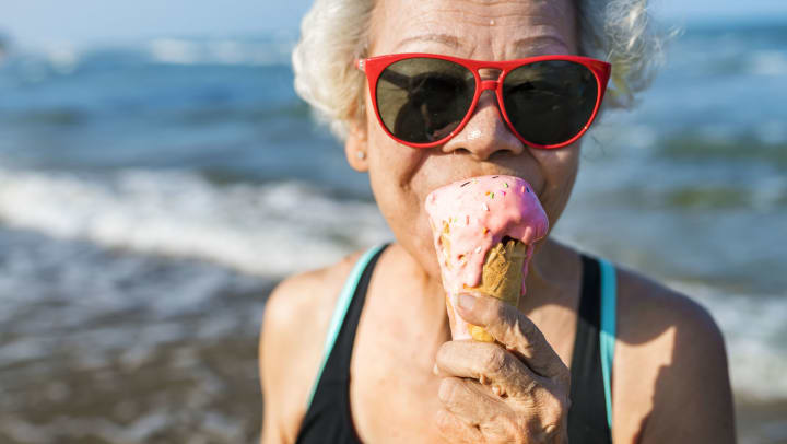 senior woman eating ice cream at the beach