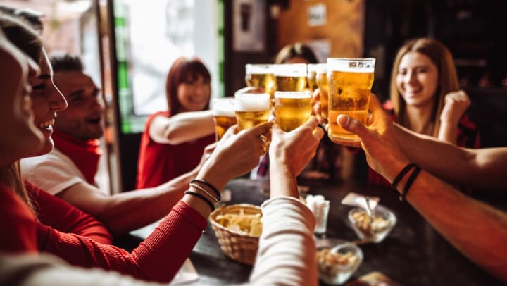  Seven people smiling and holding glasses of beer together for a toast.