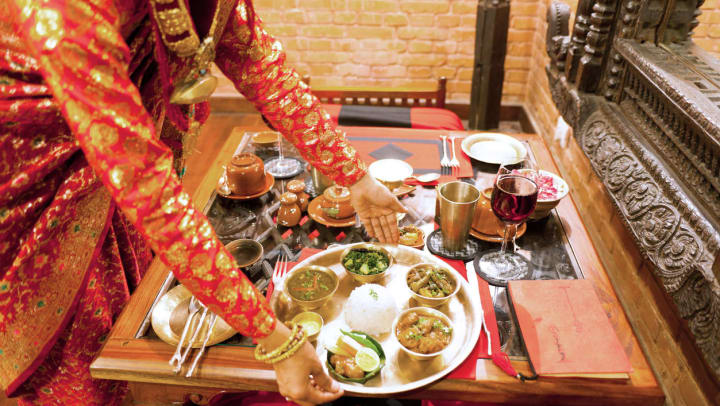 A server placing curry and rice dishes on platter at an international restaurant near Spring.