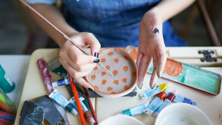 Woman hand-painting a small ceramic plate | pottery shops around Chandler