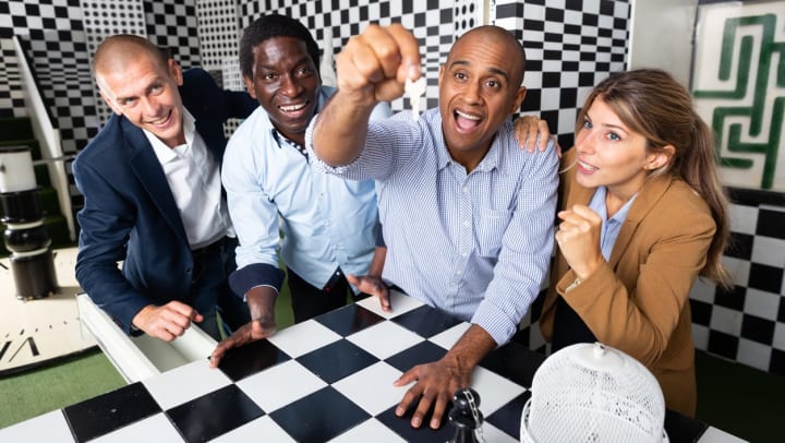 A group of four friends discovering a key in a checker patterned escape room