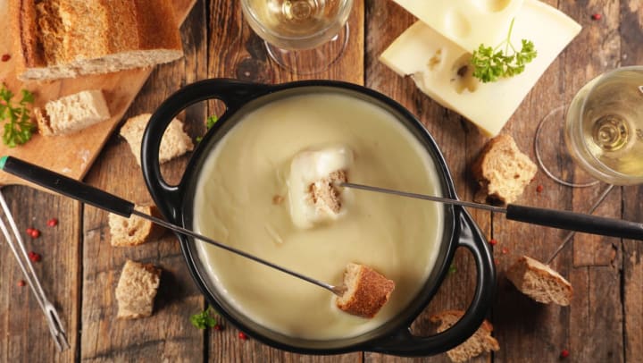 Top view of a pot of fondue with bread and white wine | Fondue Restaurants Near Willow Park