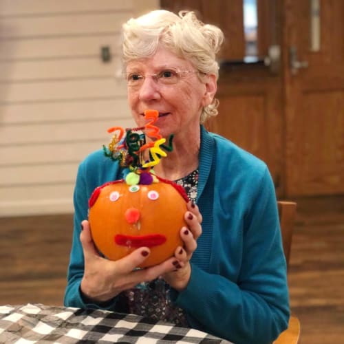 Resident showing off a decorated pumpkin at Oxford Glen Memory Care at Sachse in Sachse, Texas