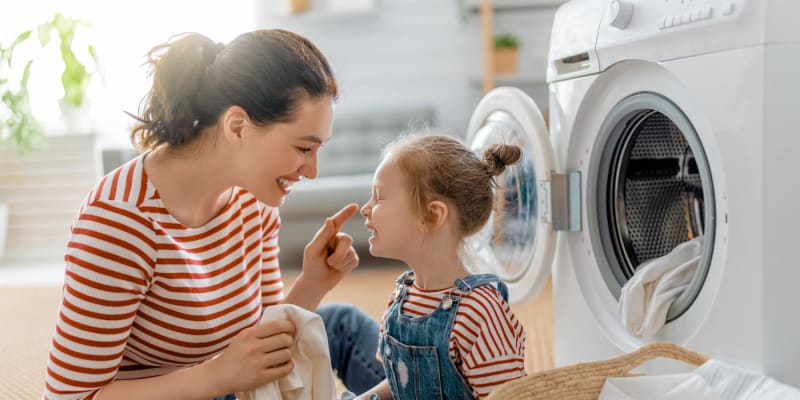 a mother and daughter smiling while doing laundry at Silver Strand II in Coronado, California