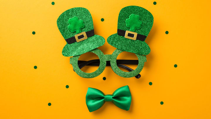 St. Patrick’s Day glasses and a green bow tie on an orange background. 